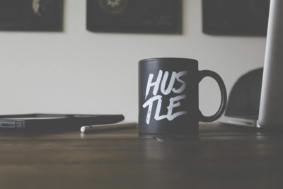 mug on a desk that says hustle