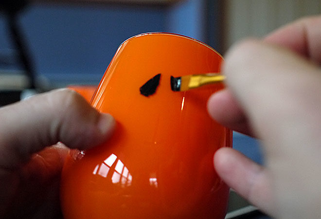 painting pumpkin faces on the outside of the glass